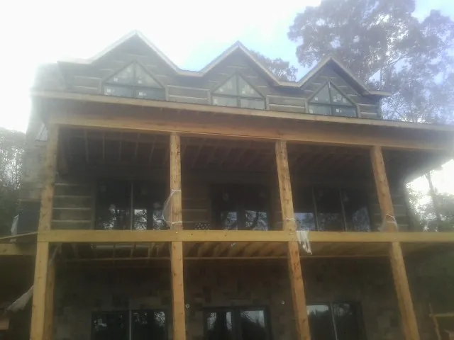 Dormers and porch framing on a large log home under construction — Roof Coating work by our crew in Taloga