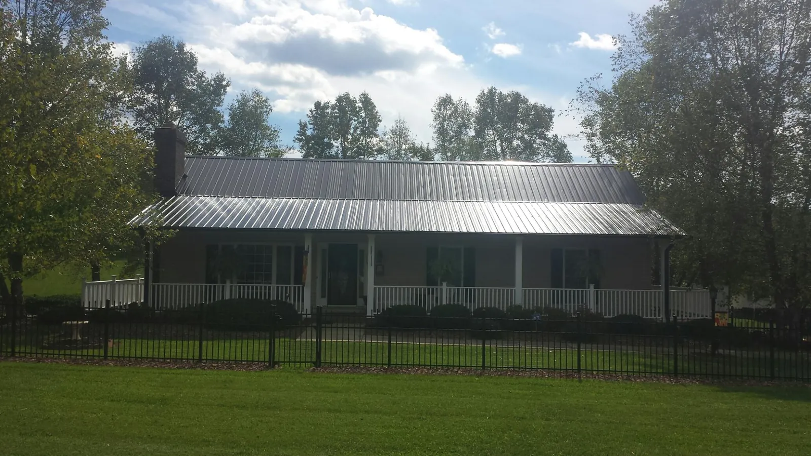 Gray metal roof on a brick ranch with a full width front porch — Gutter Guard Installation work by our crew in Taloga