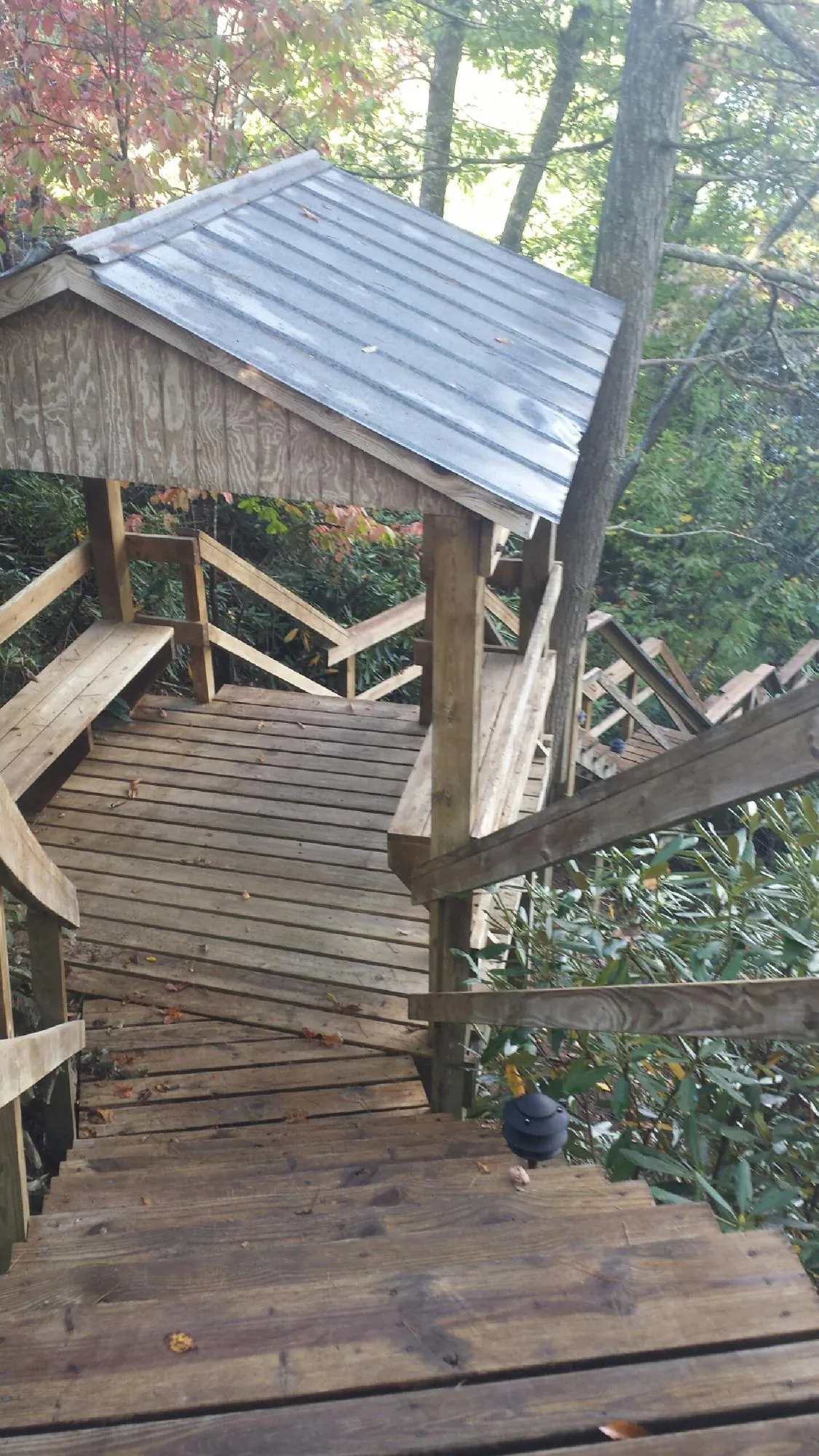 Metal roofed shelter over wooden steps on a wooded walkway — Skylight Repair & Installation work by our crew in Taloga