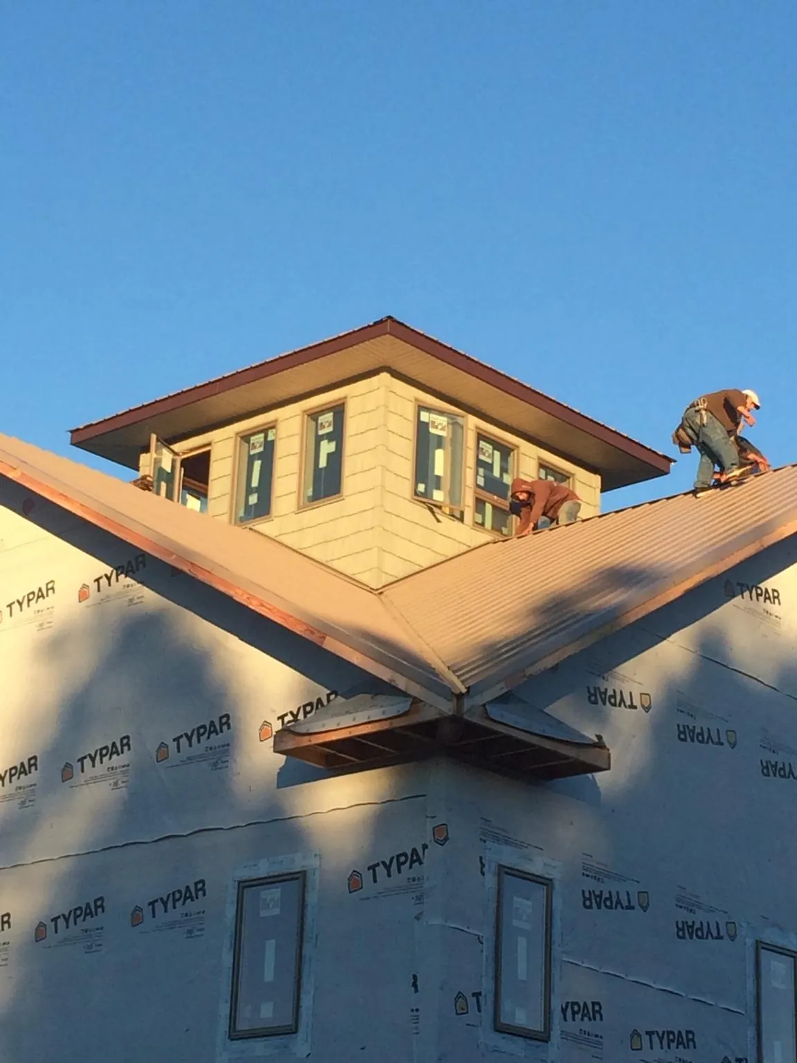 Roofers working around a rooftop cupola on a new metal roof at sunset — Roof Waterproofing in Taloga by Roofing Brothers